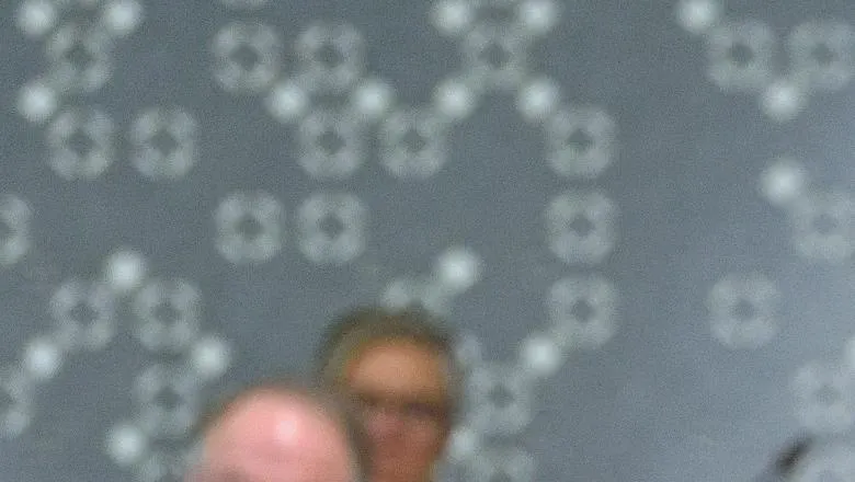 An image of Maura Scott, wearing a black dress, speaking to an audience sitting in a lecture theatre