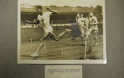 A black and white photograph of four men competing in the 100 yards.
