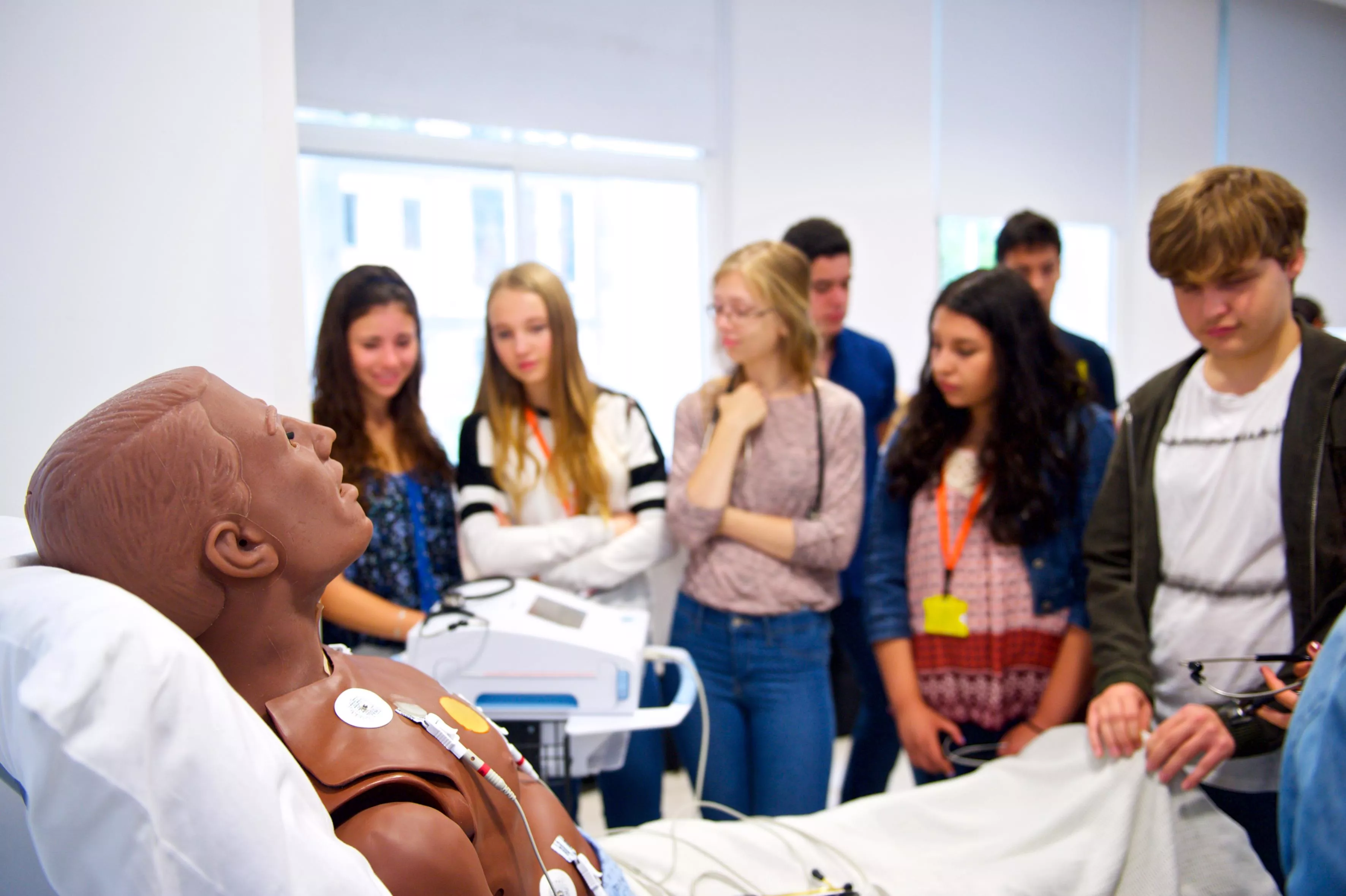 Medical Students standing around a bed containing a training manikin on a demonstration ward.