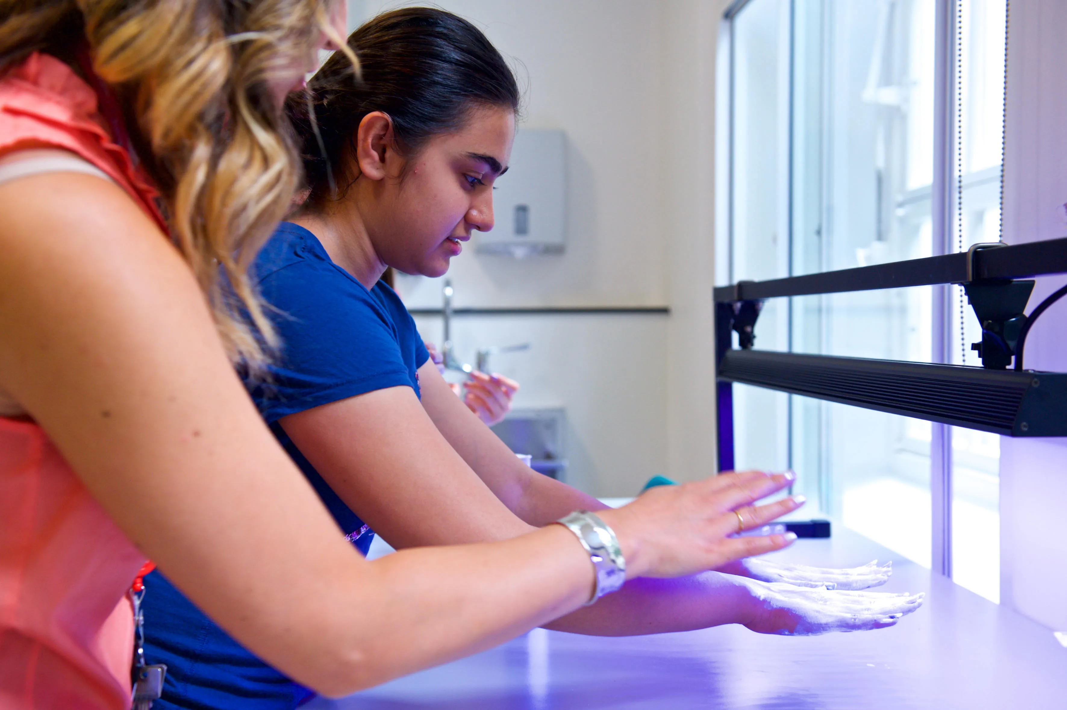 medical student examining hands under an ultra violet light