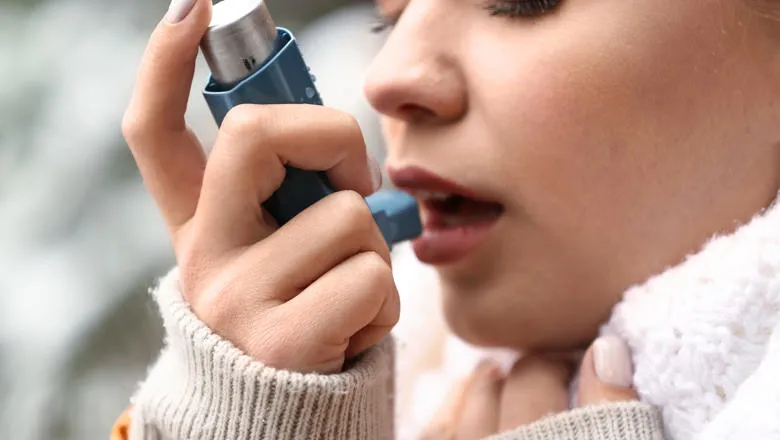Woman taking a blue asthma inhaler