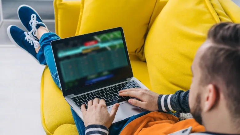 Man sat on a sofa with his laptop on a gambling website