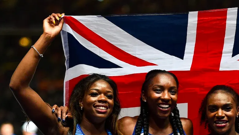 Athletes smiling while posing with united jack flag 
