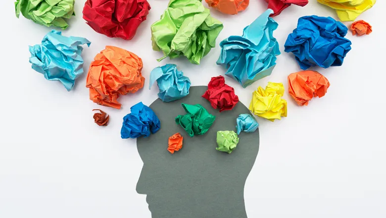 Illustration depicting mental health, with scrunched up balls of paper around a grey silhouette of a head.