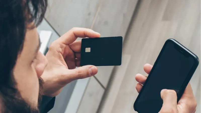 Person holding a phone in one hand and bank card in the other