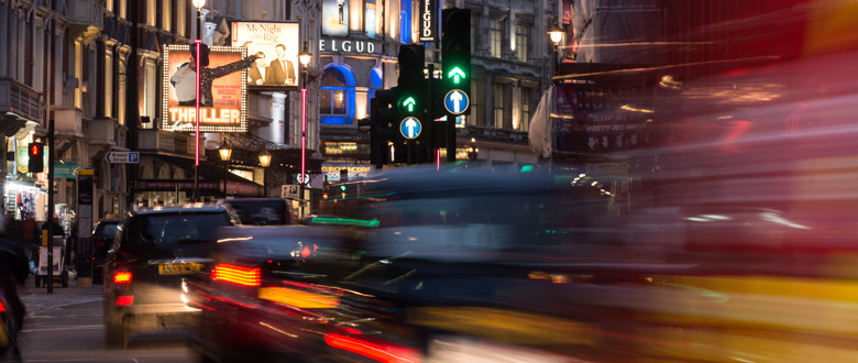 A busy London street with theatres in the background.