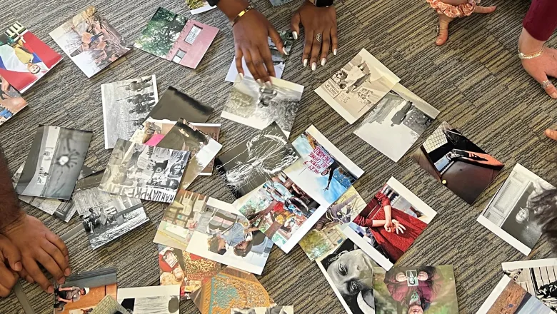 scattered photographs on a floor with hands sorting through the photographs