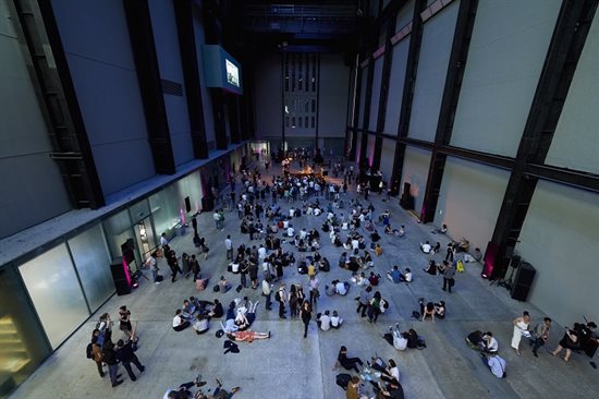 A picture of the turbine hall at Tate Modern with people standing and lying on the floor