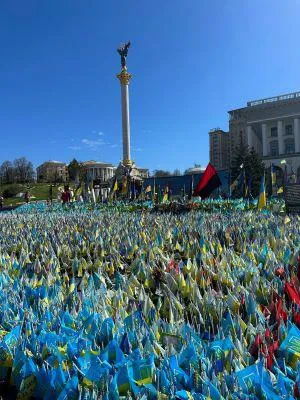 A sea of Ukrainian flags in front of a monument