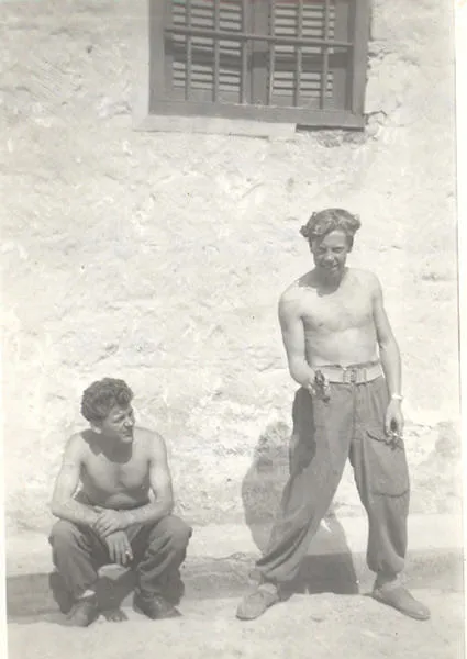 Two shirtless soldiers with cigarettes, one sitting, the other pointing a revolver at the camera. Copyright David Metters.