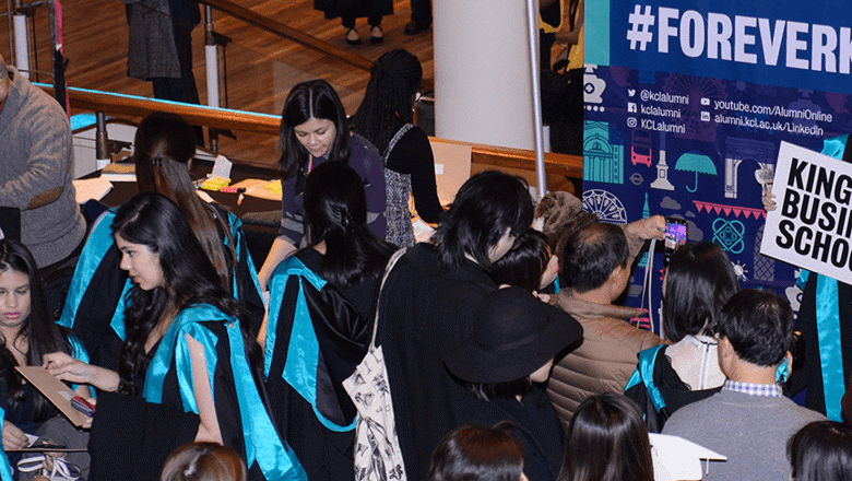 Image of King's Business School students dressed in graduation robes in a crowd of people
