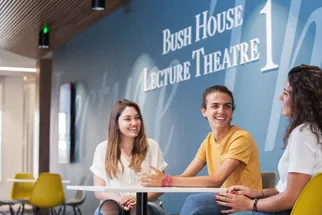 Three students sitting at desk chatting