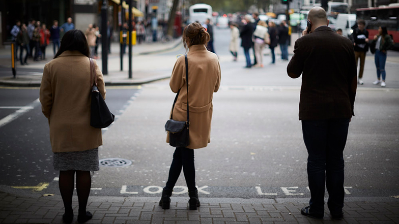 Three people waiting to cross the street