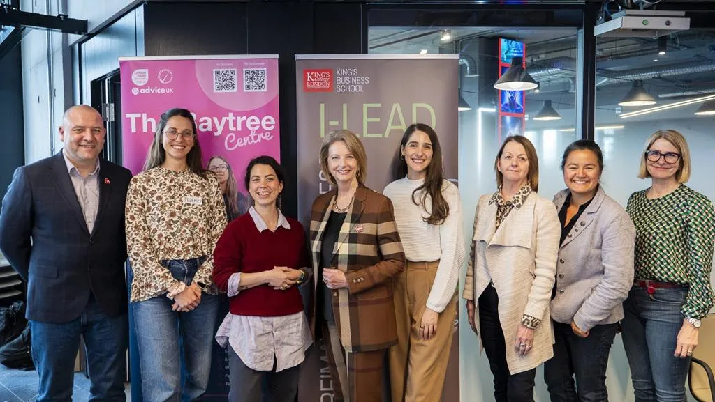 eight people in business casual clothing smile in front of two pop up stands