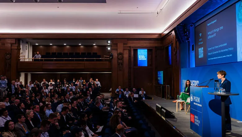 Clare Lombardelli speaks at a podium in front of a large audience