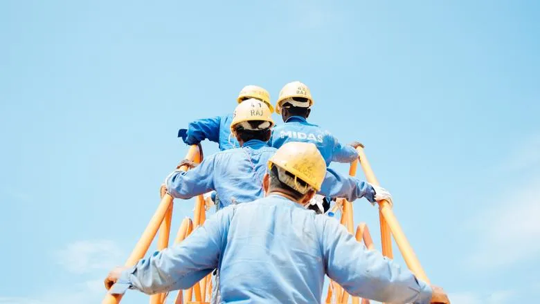 Dockworkers with helmets climb a ladder against a blue sky