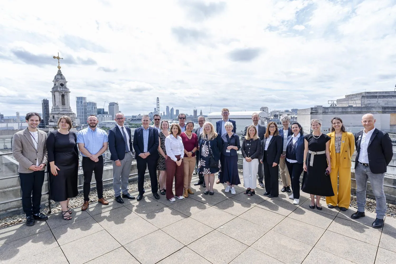 a large group in business dress pose in front of the London skyline