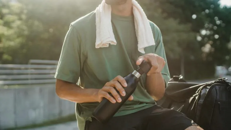 Man in Green Shirt and Black Shorts Sitting on Concrete Bench
