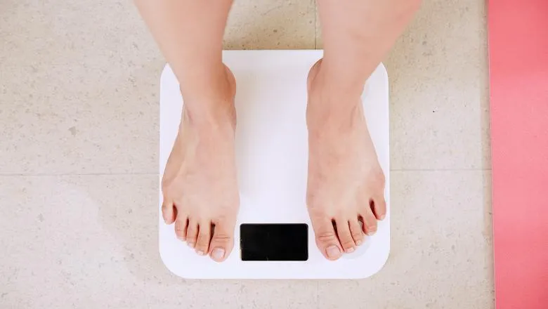 Looking down at the feet of someone standing on a set of weighing scales