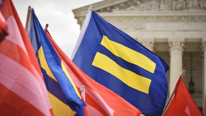 Pro-LGBTQ equality protesters wave flags outside the Supreme Court