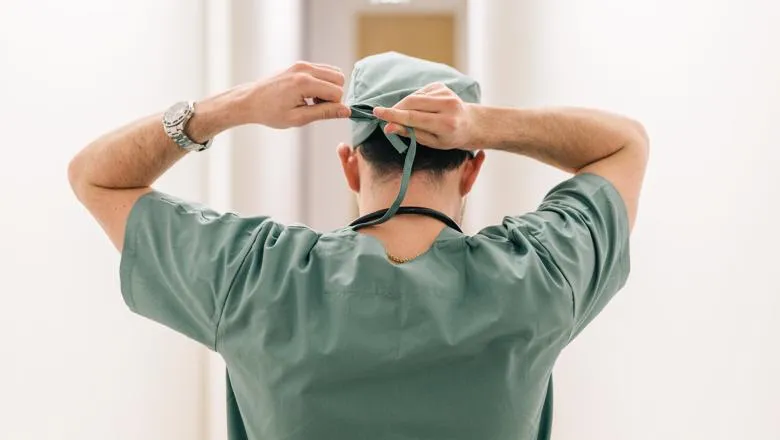 A surgeon ties their medical gap in a hospital hallway. 