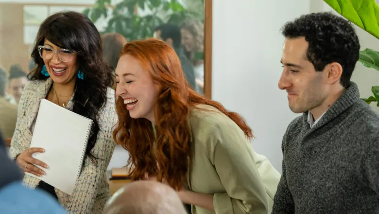 Two women and a man laughing at a meeting