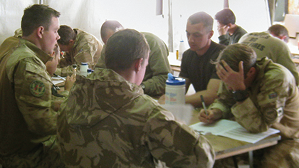 Members of the UK armed services attending a meeting in a tent