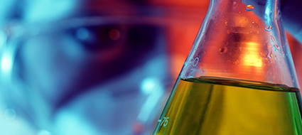 Research in lab looking at green liquid in a beaker