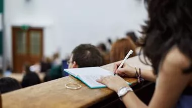 A female student writing notes in a lecture