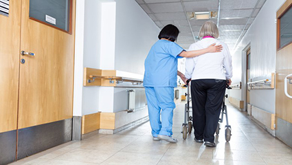 patient and healthcare practitioner walking down hospital corridor