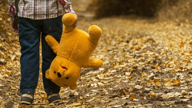 A child carrying a stuffed toy