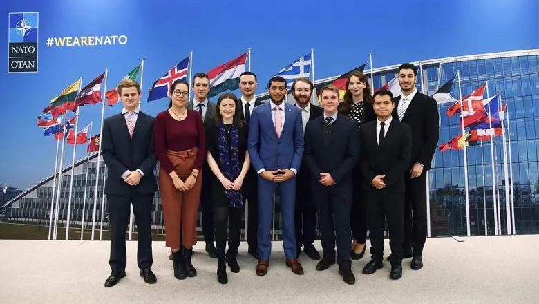 Student group photo with NATO flag backdrop 