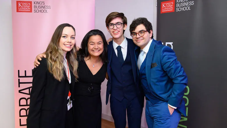 Two women and two young men in evening attire pose for a photo