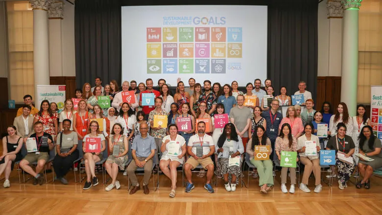 Group photo of the Sustainability Awards with people holding up SDG signs and an SDG slide in the background.
