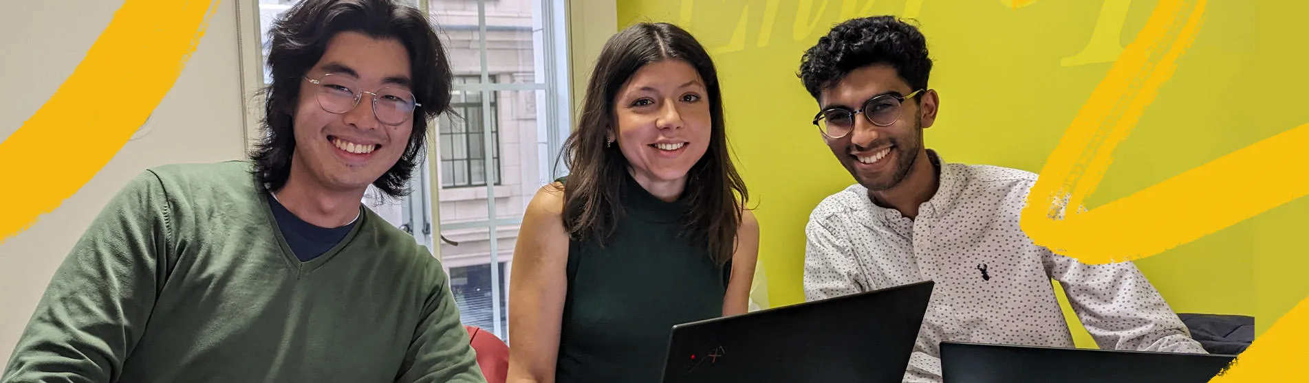 Three people sat at a table, two with laptops