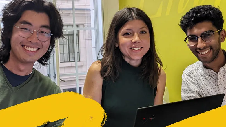 Three people sat at a table, one with a laptop