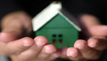 Hands holding a small green house
