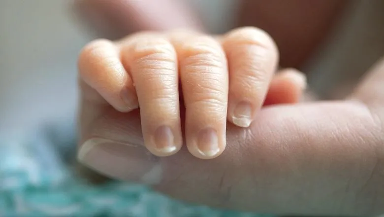 An image of a newborn babies hand holding on to an adult finger
