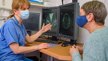 A doctor treating a patient. Both are wearing face coverings.