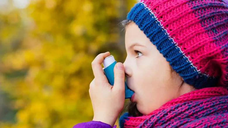 A young girl using an asthma inhaler.