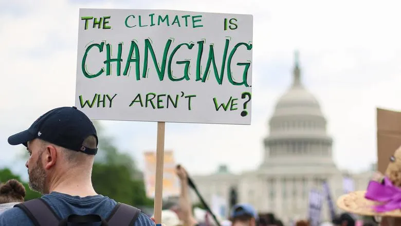 A man holding a sign that says: The climate is changing. Why aren't we?