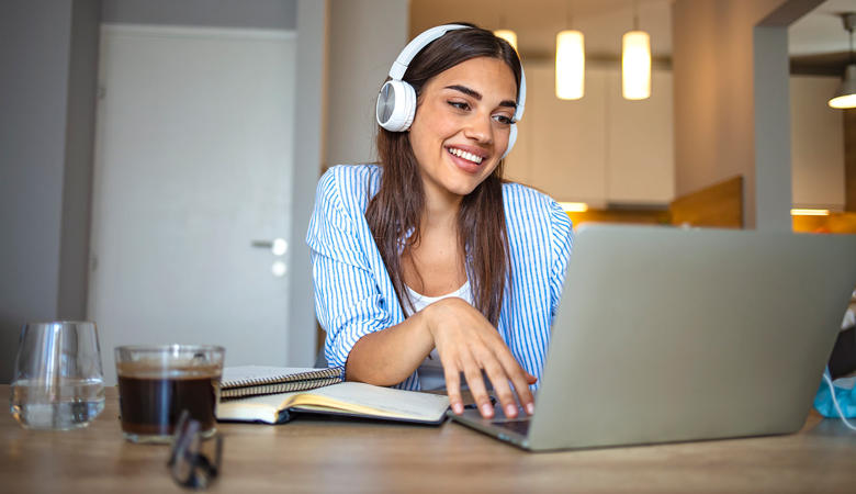 A woman wearing headphones and using a laptop.
