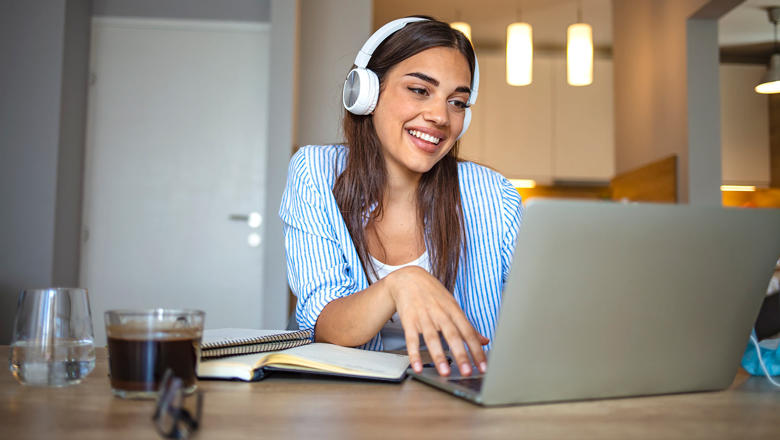 A woman wearing headphones and using a laptop.