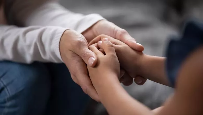 Child's hands in adult's hands