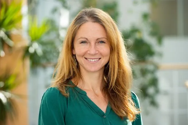 Woman smiling in front of leaves