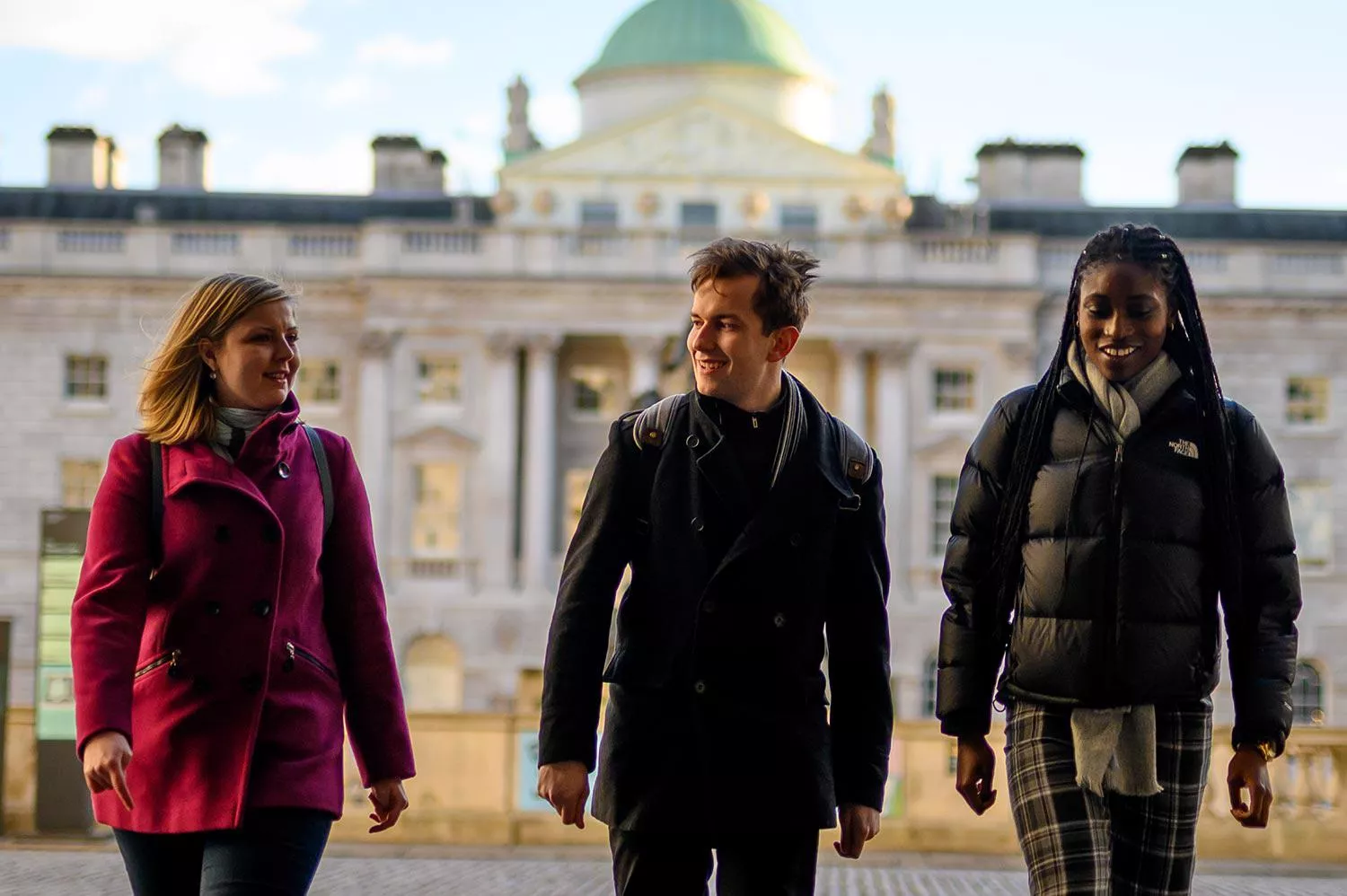 Three students walking through the courtyard of Somerset House.