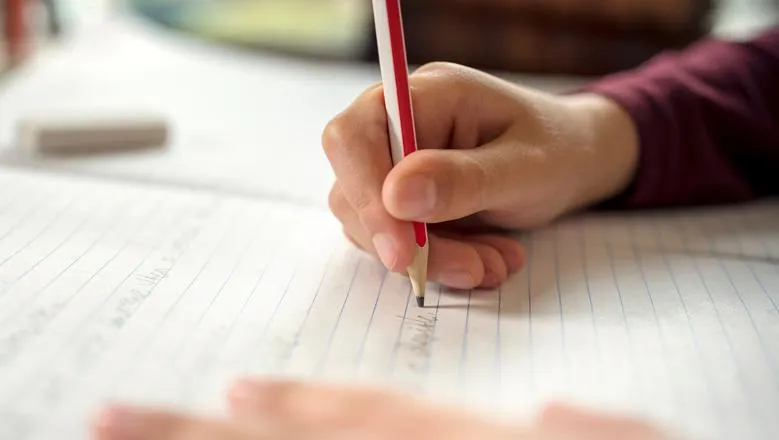 Hand using pencil to write on paper