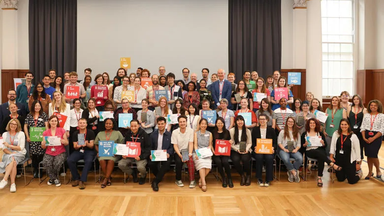 Group photo taken at the sustainability awards 2023 showing about 100 people holding up SDG boards.
