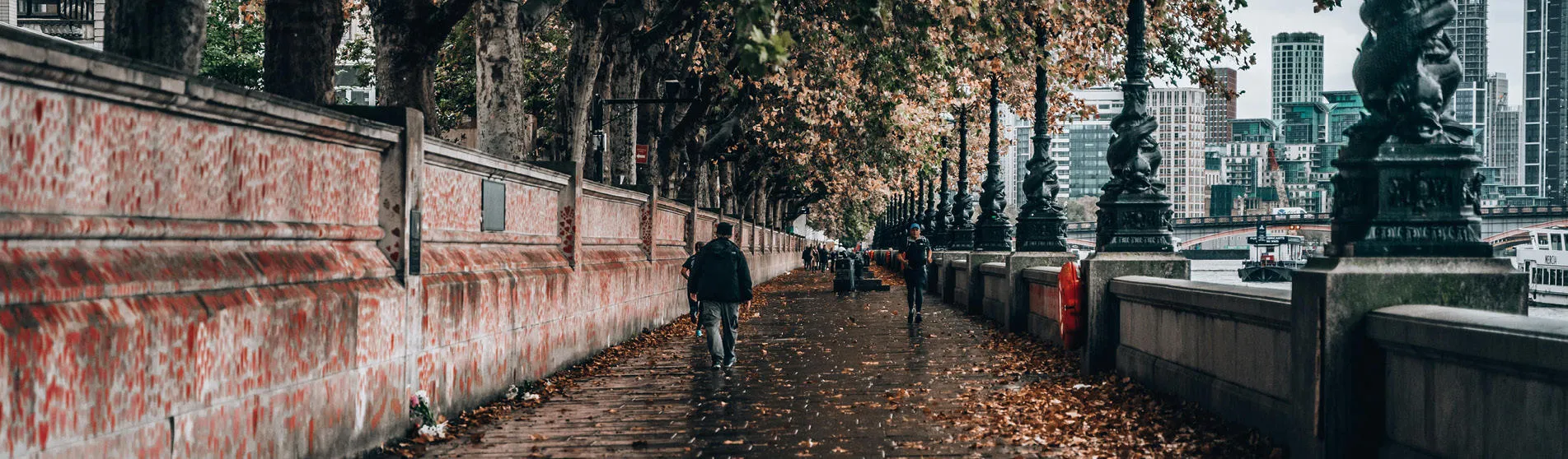 Path along the River Thames outside of St Thomas' Campus in Autumn, along the COVID-19 Memorial wall. People are walking along the path in the distance.