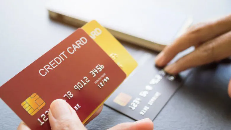 Finger holding Credit card with blur Smartphone on black wooden table background